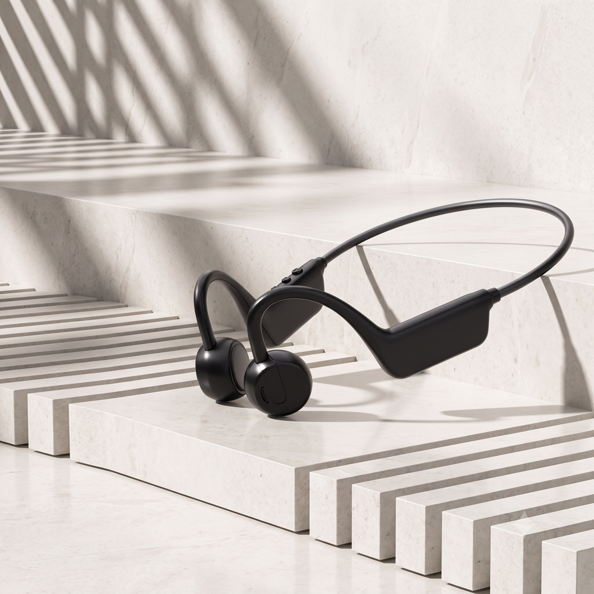 Black bone conduction wireless earplugs resting on a modern, minimalist white marble staircase with dramatic diagonal shadows.