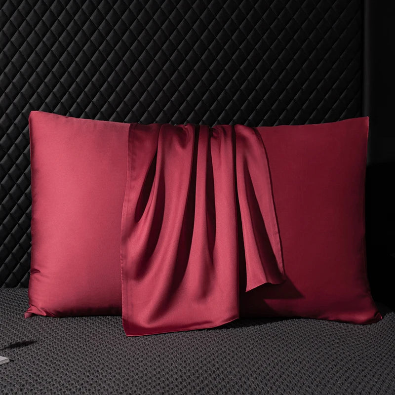 Two red satin pillows on a textured black surface