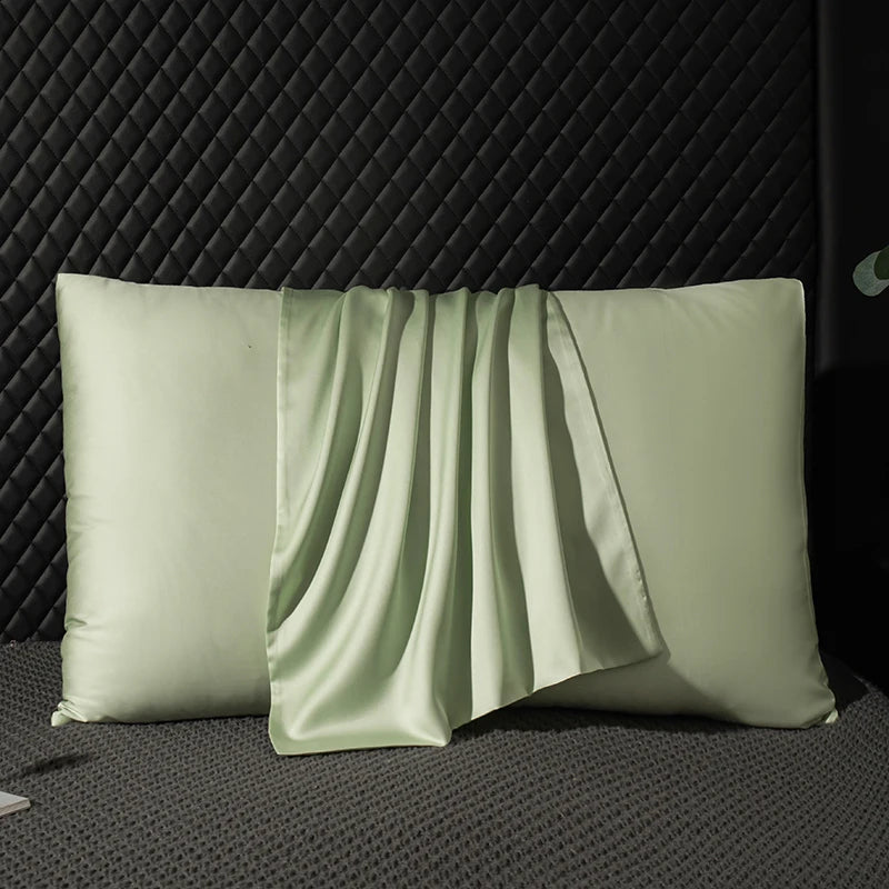 Two green satin pillows on a textured black surface