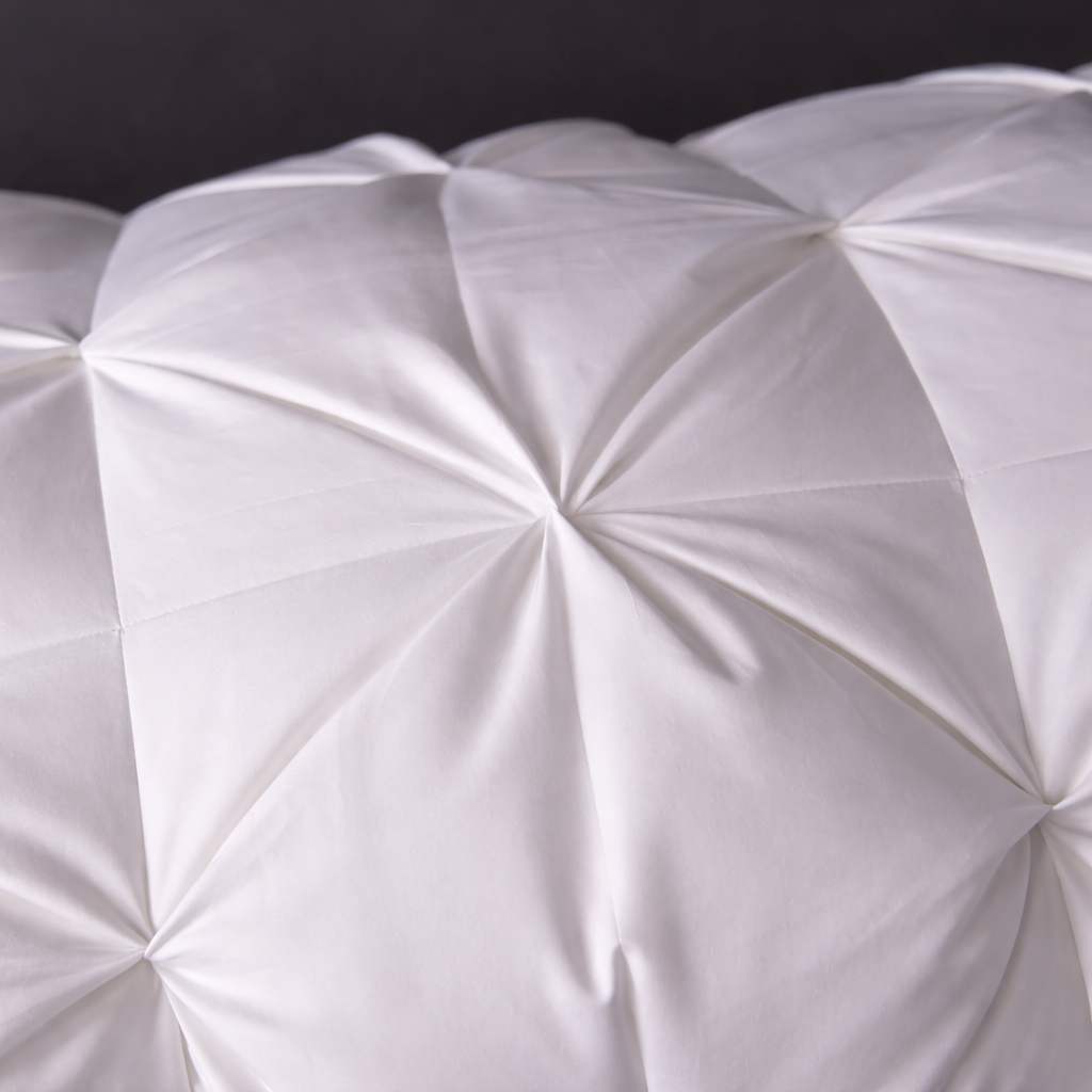 Close-up of a white quilted pillow against a dark background